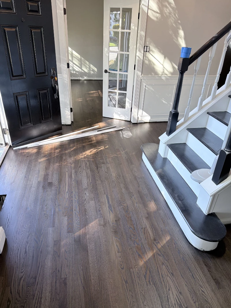 Entry hall with refinished dark oak floor meeting a white staircase
